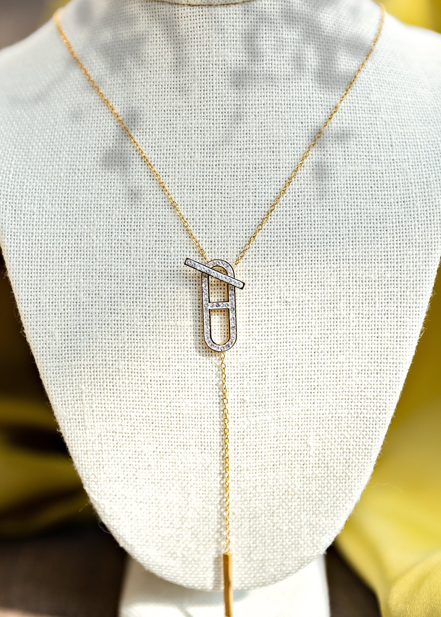 Gold necklace with a unique pendant on a mannequin bust.