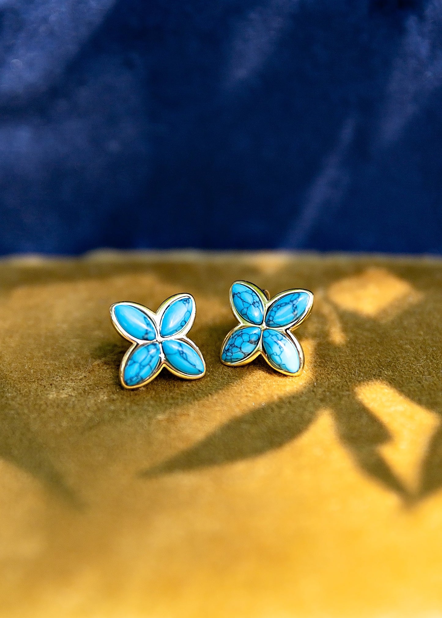 Turquoise butterfly earrings on a gold and blue background