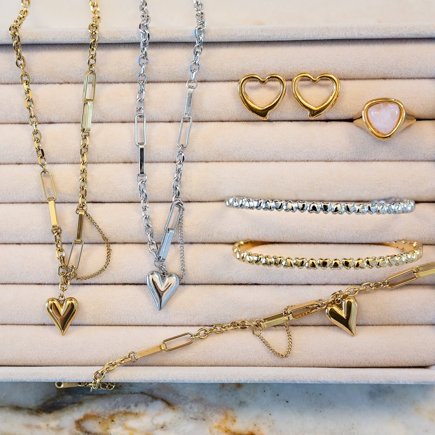 Jewelry set including heart pendant necklaces and heart-shaped earrings on a suede jewelry tray.
