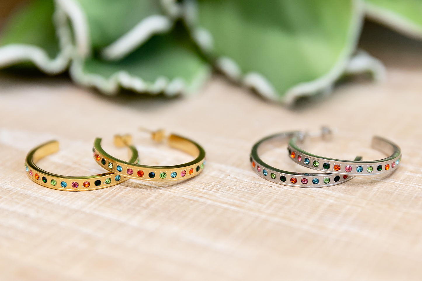 Two gold and silver bangles with colorful stones on a beige surface.