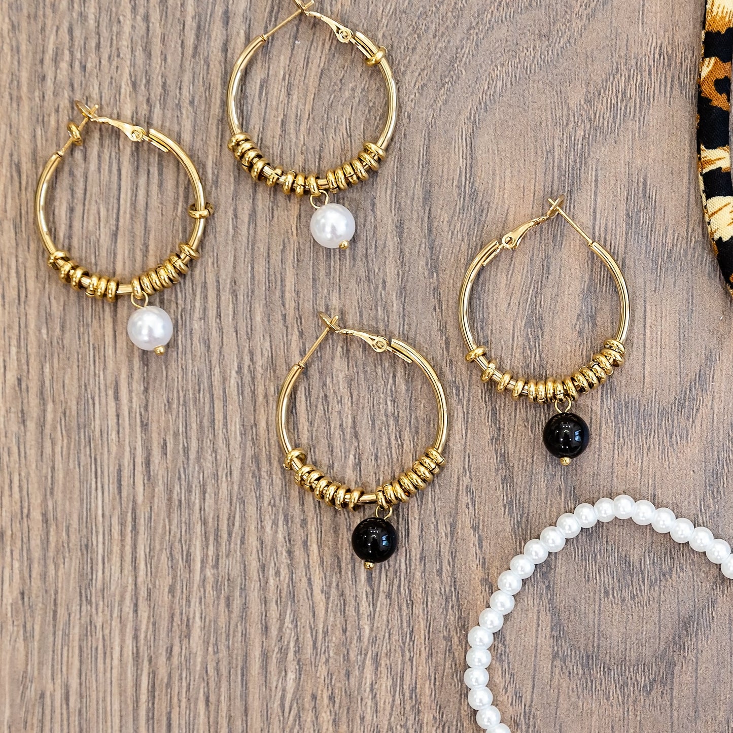 Jewelry set including hoop earrings, a necklace, and bracelets on a wooden surface