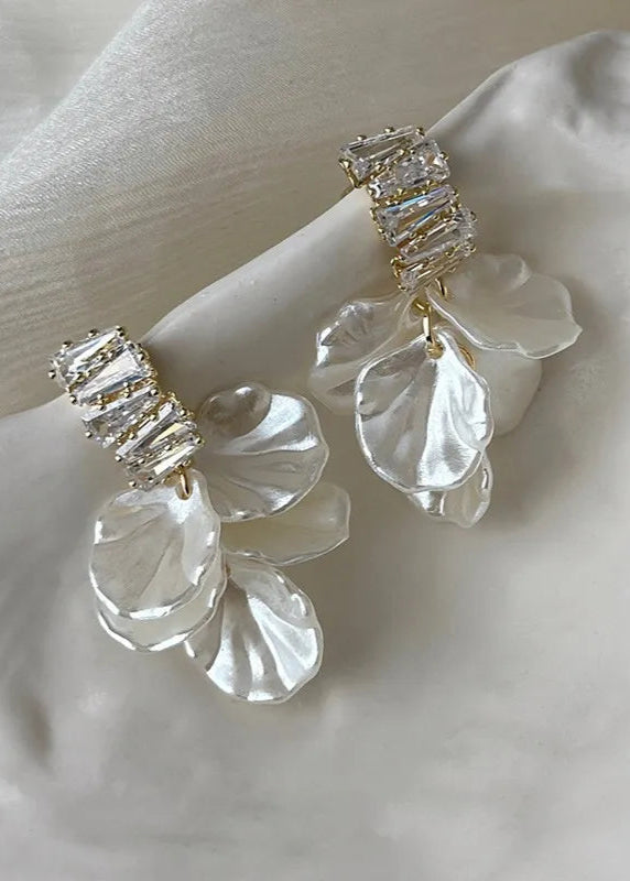 A pair of white mother of pearl shell earrings with 18kt gold plating and baguette CZ stones, displayed on a mannequin.