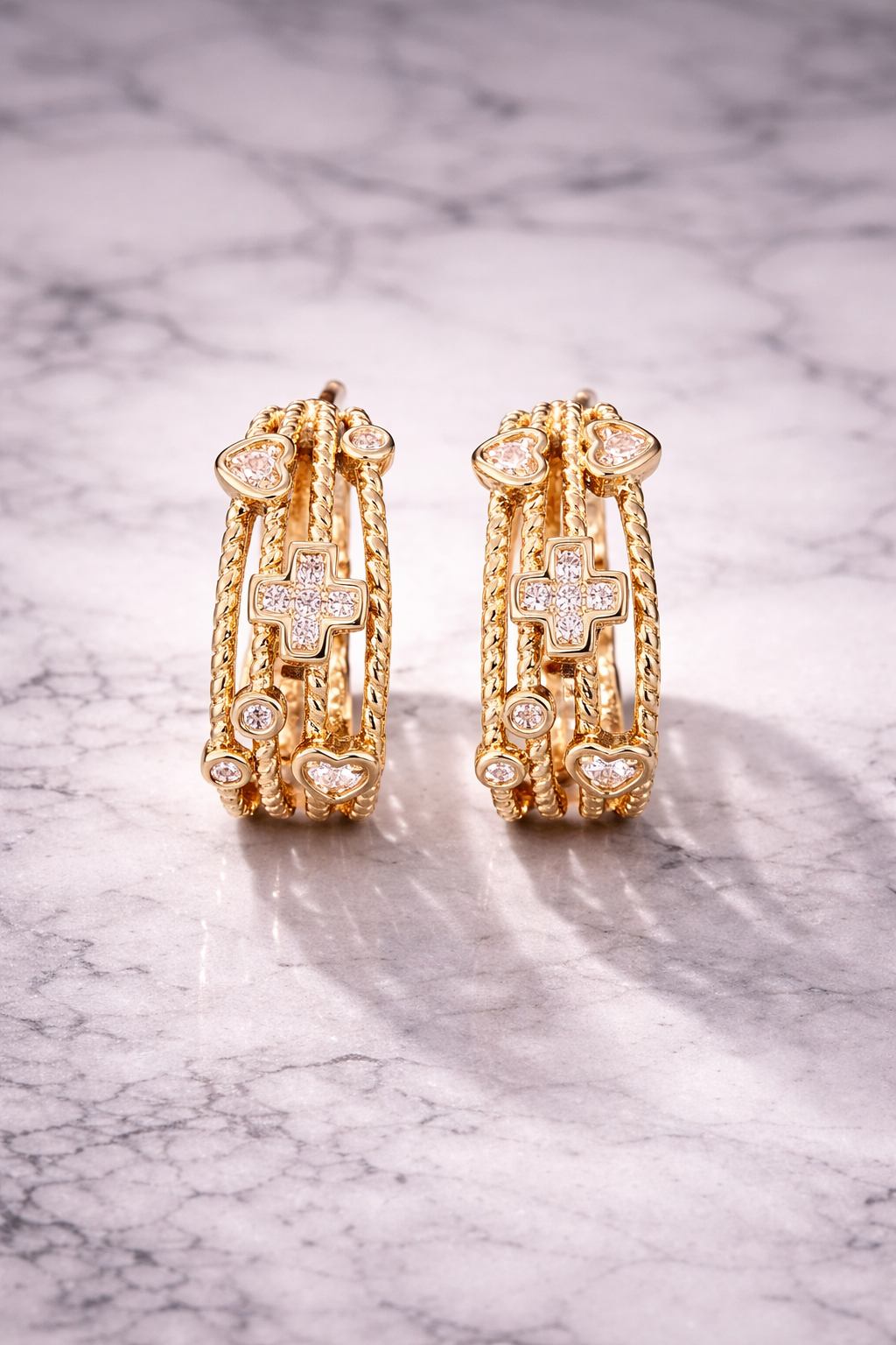 VEITA Jewelry gold chunky multi-strand hoop earrings with pavé CZ cross and heart charms displayed on marble surface