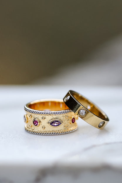 Angled view of gold ring showing textured band and multicolor stones