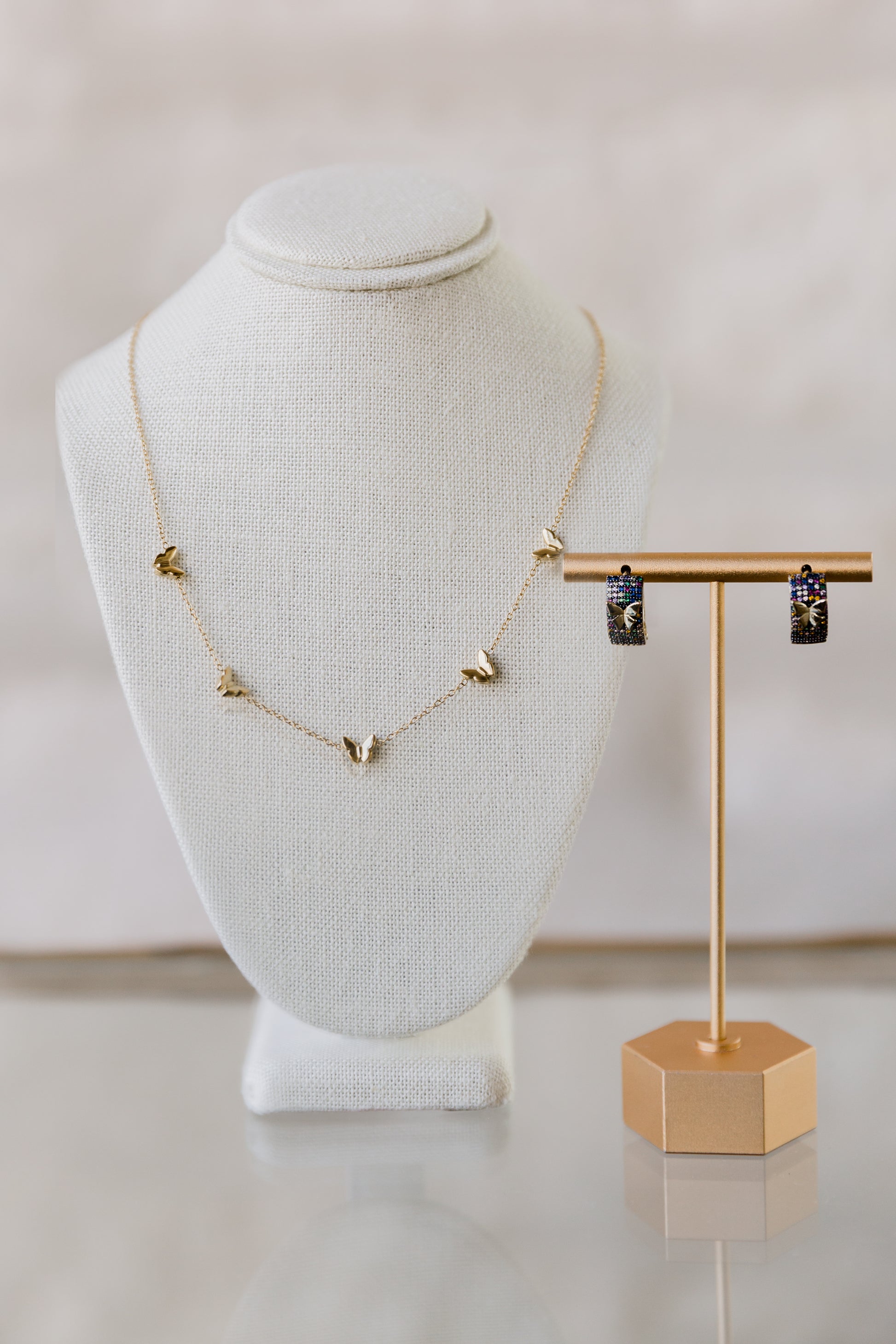 Mora butterfly earrings paired with Andrea Butterfly Necklace on display bust, showcasing multicolor zircon stones and delicate gold design