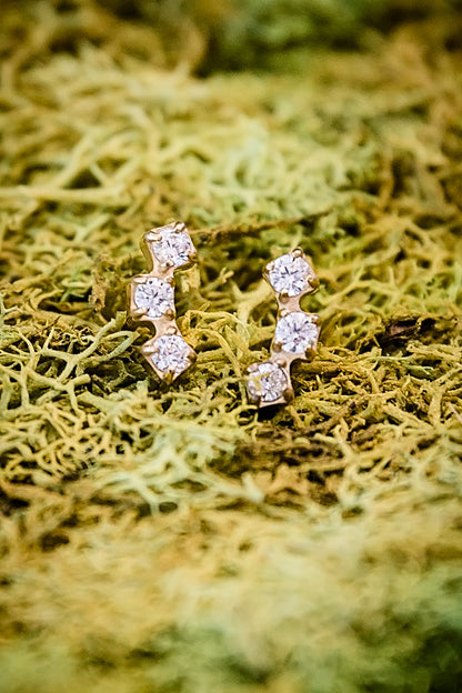 Tiny zircon stud earrings arranged on moss background, showing minimal and delicate design for everyday wear