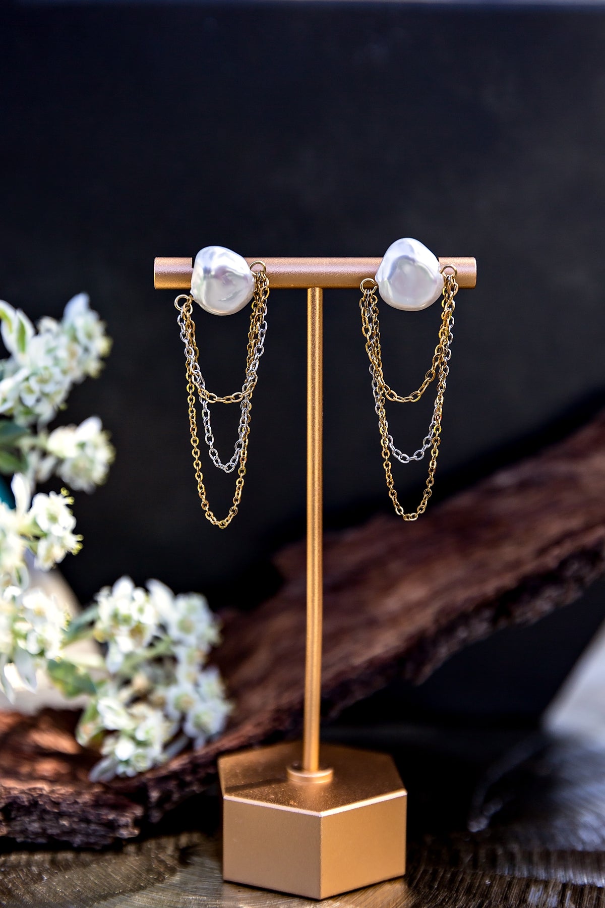 Aurelia Earrings from the LUNA Collection featuring faux pearl studs with delicate draped mixed-metal chains, displayed on an earring stand.