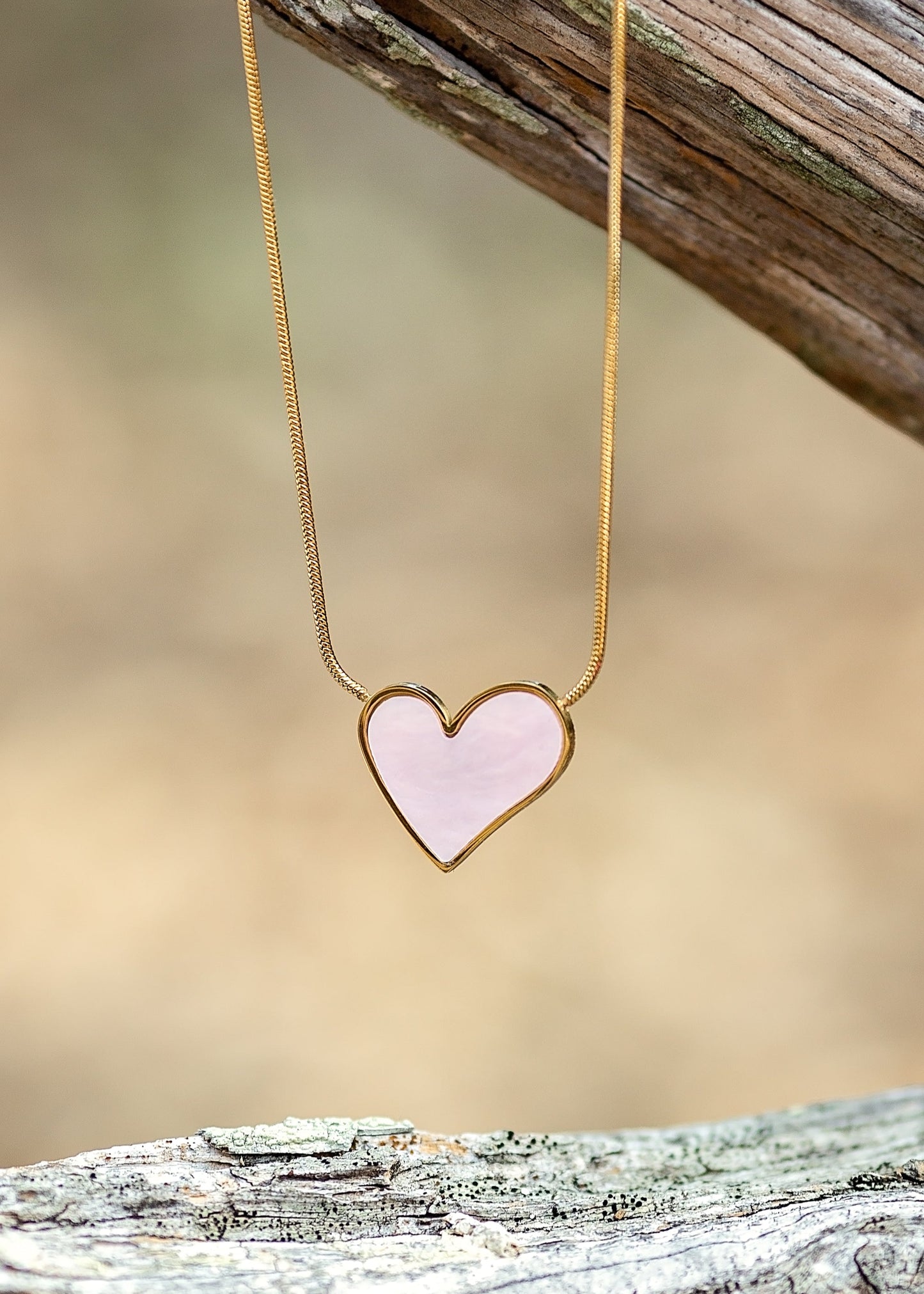 Heart-shaped pendant necklace on a wooden surface with a blurred natural background