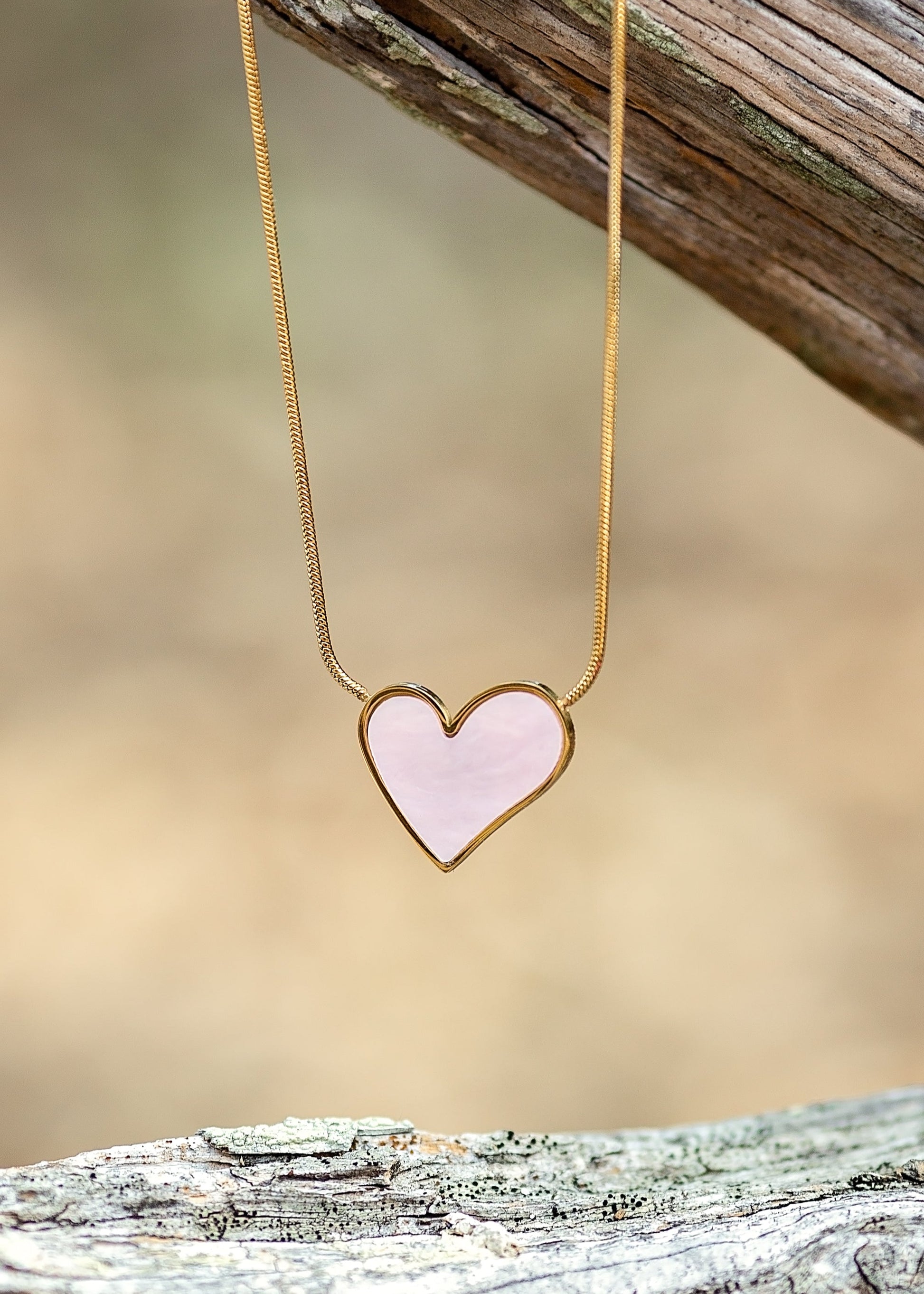 Heart-shaped pendant necklace on a wooden surface with a blurred natural background