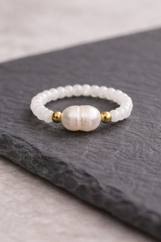 Pearl ring with gold accents on a dark surface