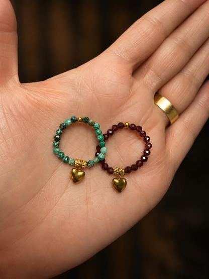Close-up of the Claire Stretch Ring featuring faceted natural gemstone beads, a gold heart charm, and 18kt gold-plated stainless steel accents worn on hand.