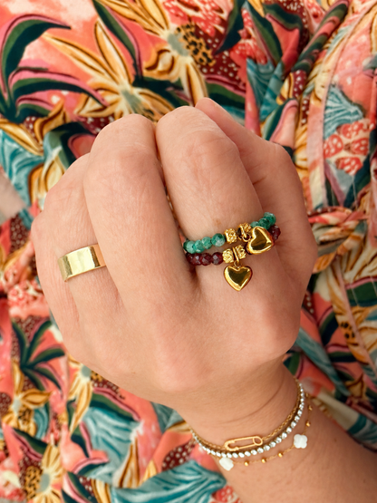 Model wearing both colors of the Claire Stretch Ring featuring faceted natural gemstone beads, a gold heart charm, and 18kt gold-plated stainless steel accents.