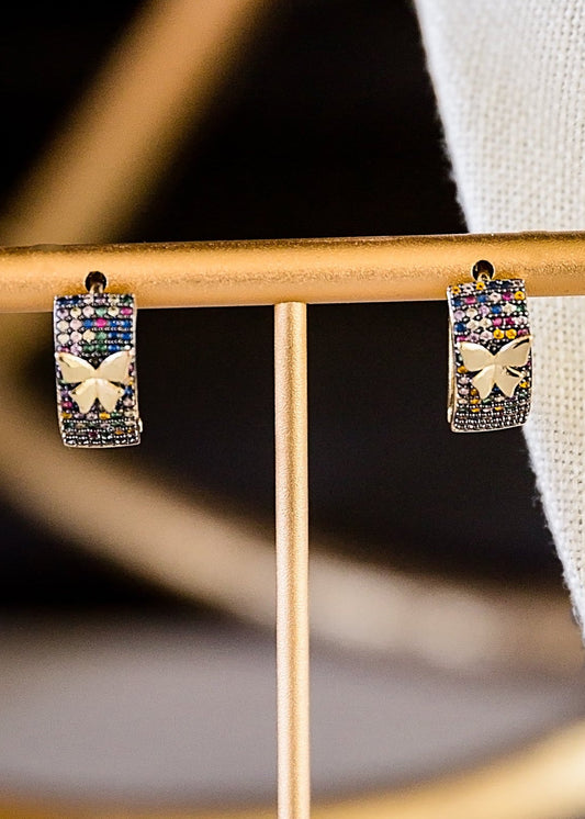 Closeup Mora butterfly earrings with multicolored zircon stones displayed on gold stand, featuring 14kt gold plated brass design