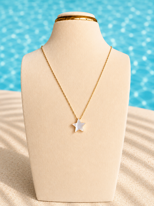 Estrela Necklace featuring a natural white shell star pendant on an 18kt gold-plated chain displayed on a jewelry bust in a beach-inspired setting.