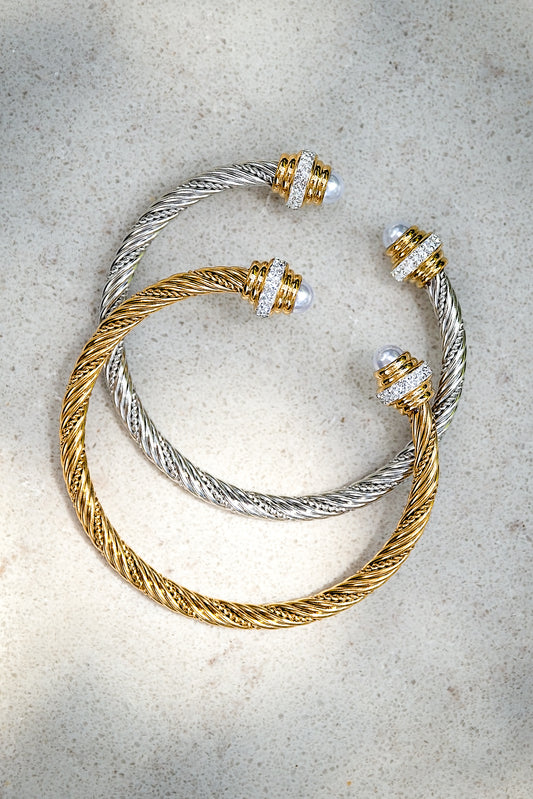 Two gold and silver bracelets on a textured surface