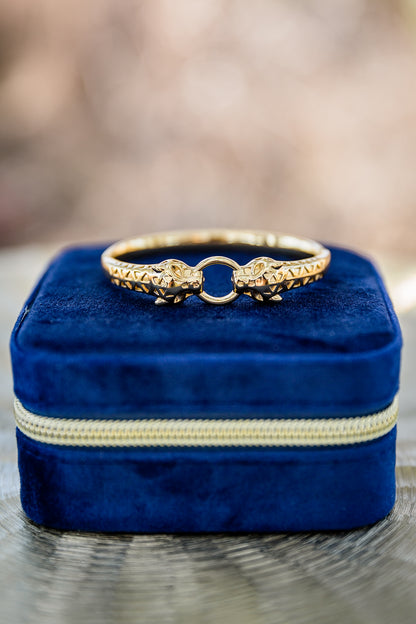 Gold feline bangle placed on a white jewelry box, highlighting polished finish and sculptural animal-inspired design