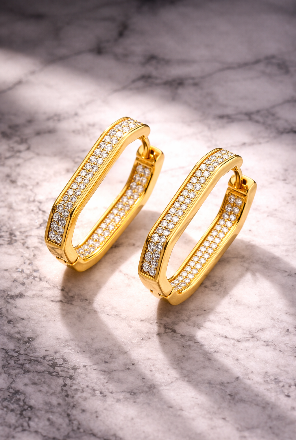 Gold hoop earrings with embedded diamonds on a marble surface