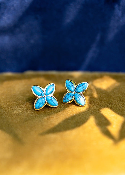 Turquoise butterfly earrings on a gold and blue background