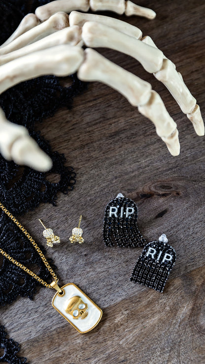 VEITA Jewelry Skull Micro Stud Earrings styled with gold-toned accessories and rustic decorative elements, showcasing their petite statement design.