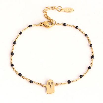 Gold bracelet with black beads and a ghost charm on a white background