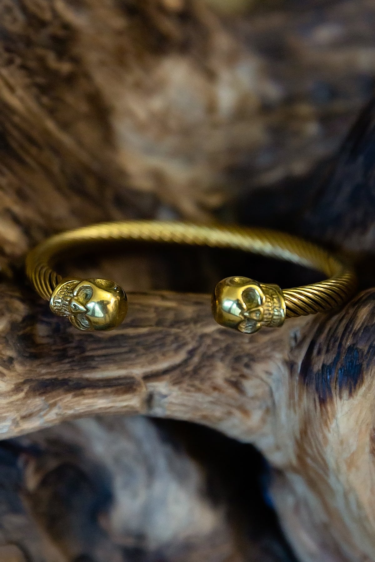 Gold bracelet with skull designs on a wooden surface