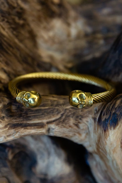 Gold bracelet with skull designs on a wooden surface