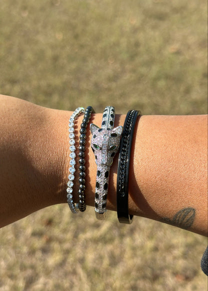 Wrist with multiple bracelets against a blurred natural background