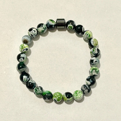 Beaded bracelet with green and black beads on a beige background