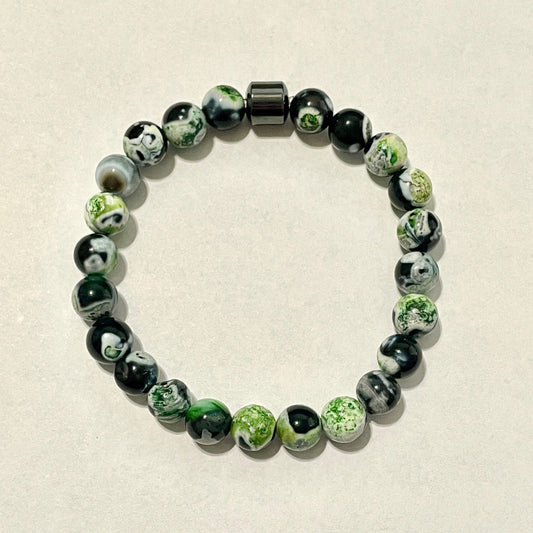 Beaded bracelet with green and black beads on a beige background