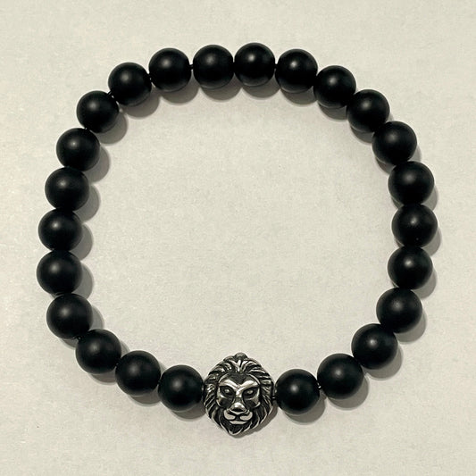 Black beaded bracelet with a lion head charm on a beige background