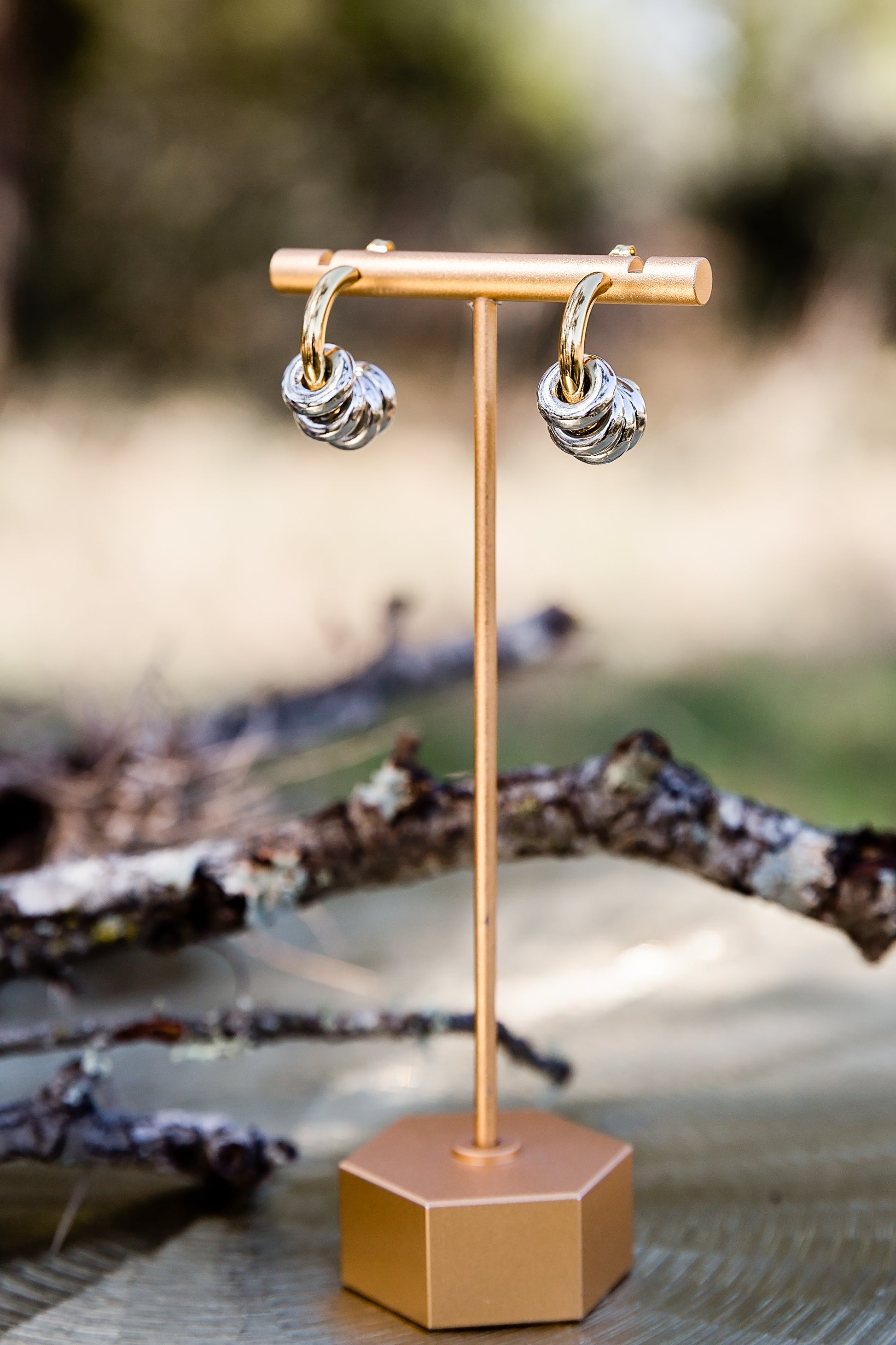Inez hoop earrings displayed on stand featuring bold mixed metal design with removable ring details