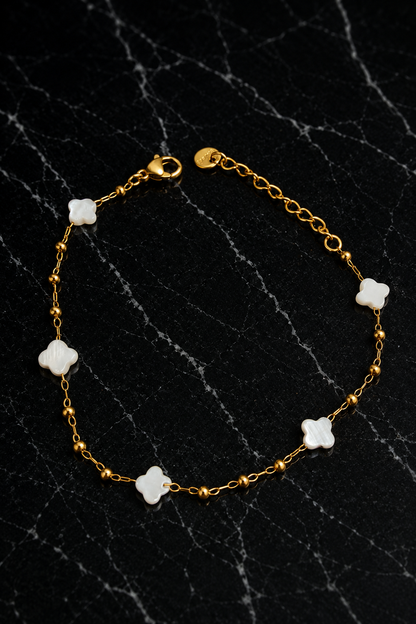 Kate Layering Bracelet featuring delicate mother of pearl accents on an 18kt gold-plated stainless steel chain displayed on a black marble surface.
