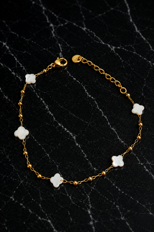 Kate Layering Bracelet featuring delicate mother of pearl accents on an 18kt gold-plated stainless steel chain displayed on a black marble surface.