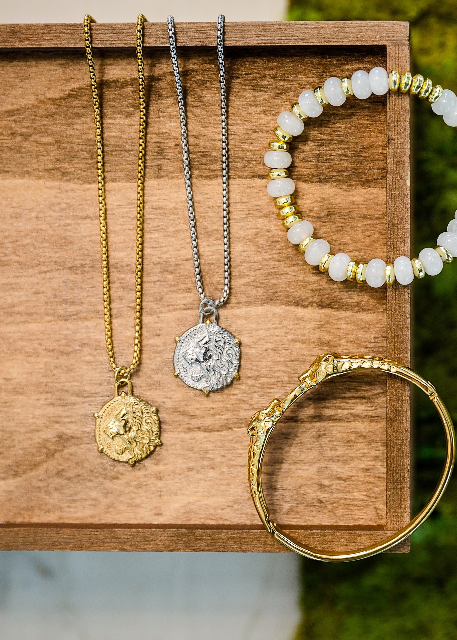 Mother of pearl pendant necklace styled with bracelet and accessories on wood surface