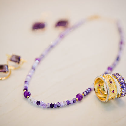 Midnight Orchid necklace styled with layered gold jewelry highlighting vibrant purple stones and textured design