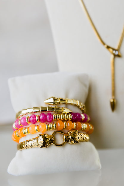 Night Coil gold bangle styled with colorful bracelets in a stacked wrist look highlighting versatile layering options
