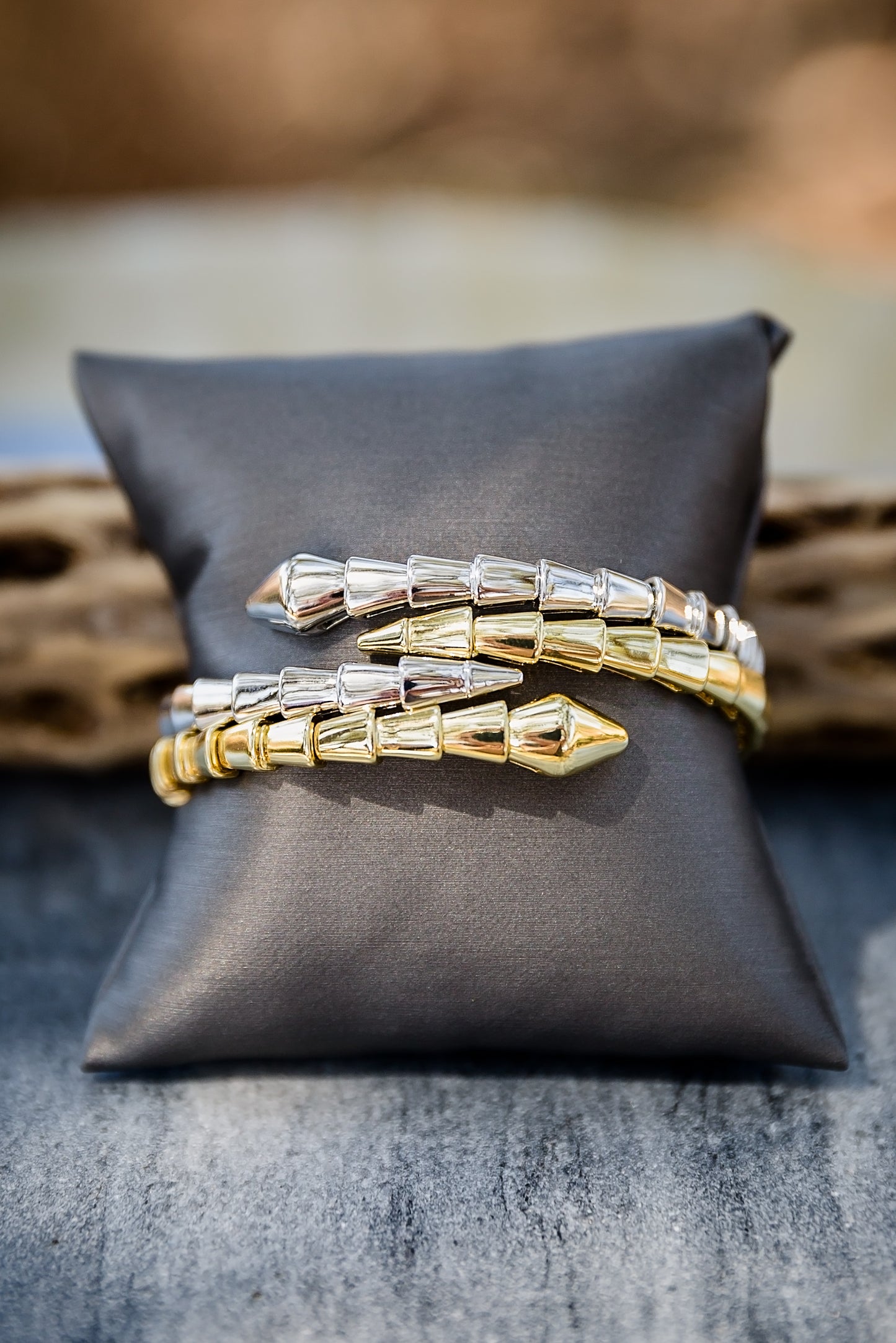 Stacked Night Coil bangles on display pillow showing layered styling with textured coil design and gold finish