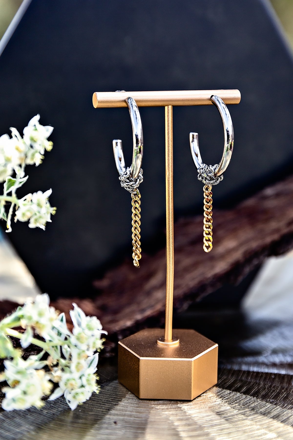 Nikola Hoops from the LUNA Collection featuring silver-tone hoops with dangling gold chain-link details, displayed on an earring stand.