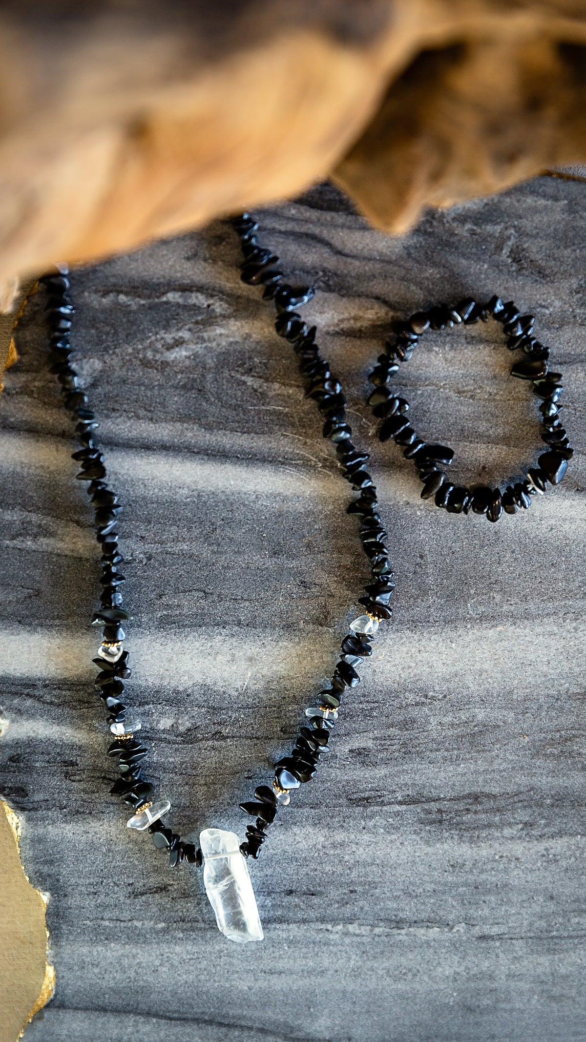 Close-up styled view of the Noir Necklace showing black obsidian stones and raw crystal pendant.