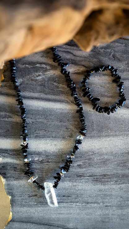 Close-up styled view of the Noir Necklace showing black obsidian stones and raw crystal pendant.