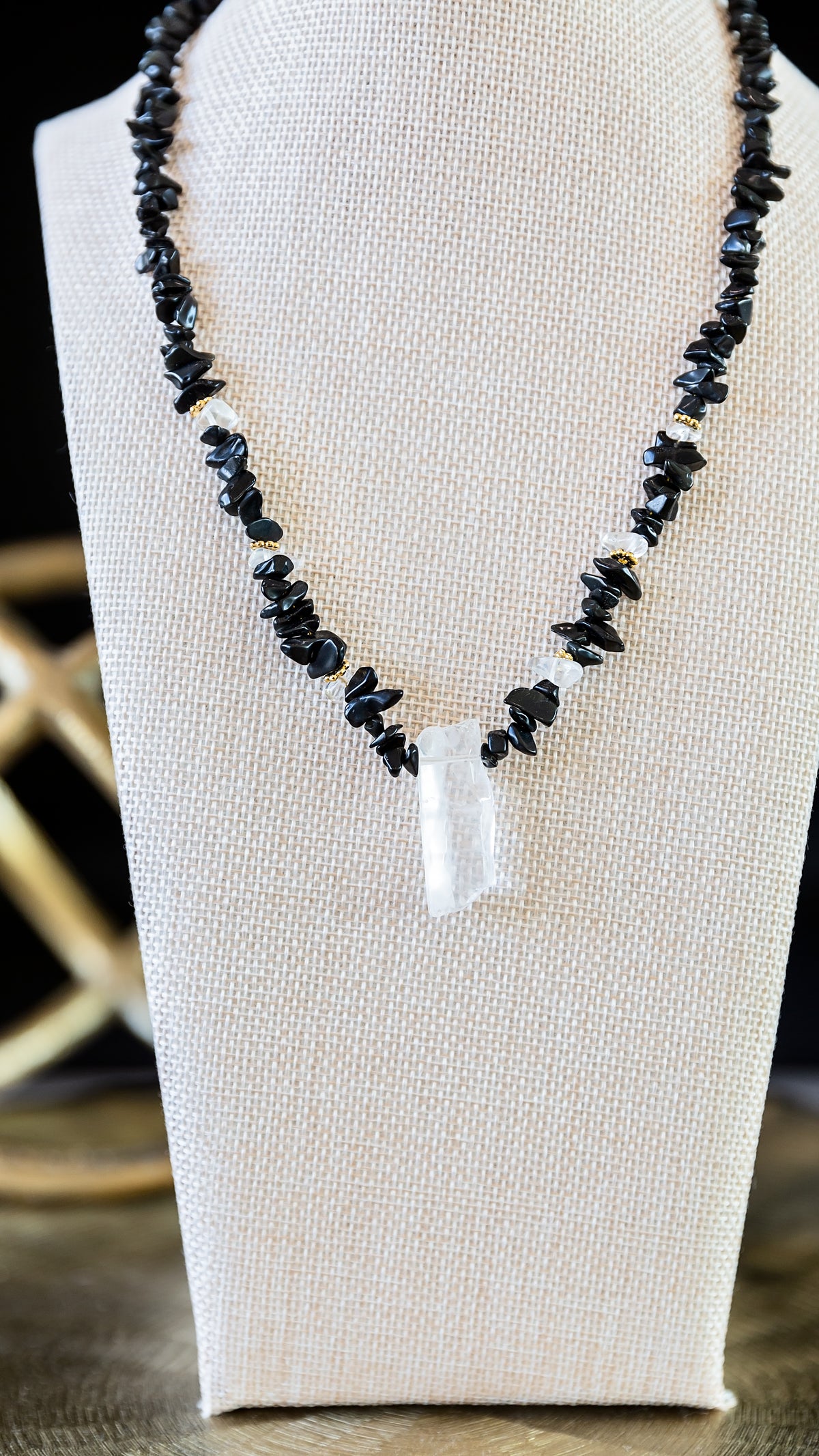Noir Necklace featuring genuine black obsidian stones and a raw crystal pendant displayed on a jewelry bust.