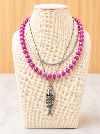 Pesce d'Oro Necklace layered with colorful beaded necklaces, showcasing its textured fish pendant and effortless coastal-inspired style.