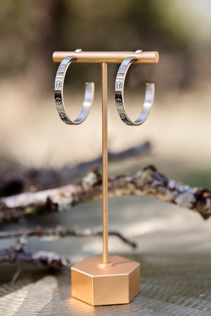 Sabine statement hoop earrings displayed on stand featuring textured gold design and bold polished finish