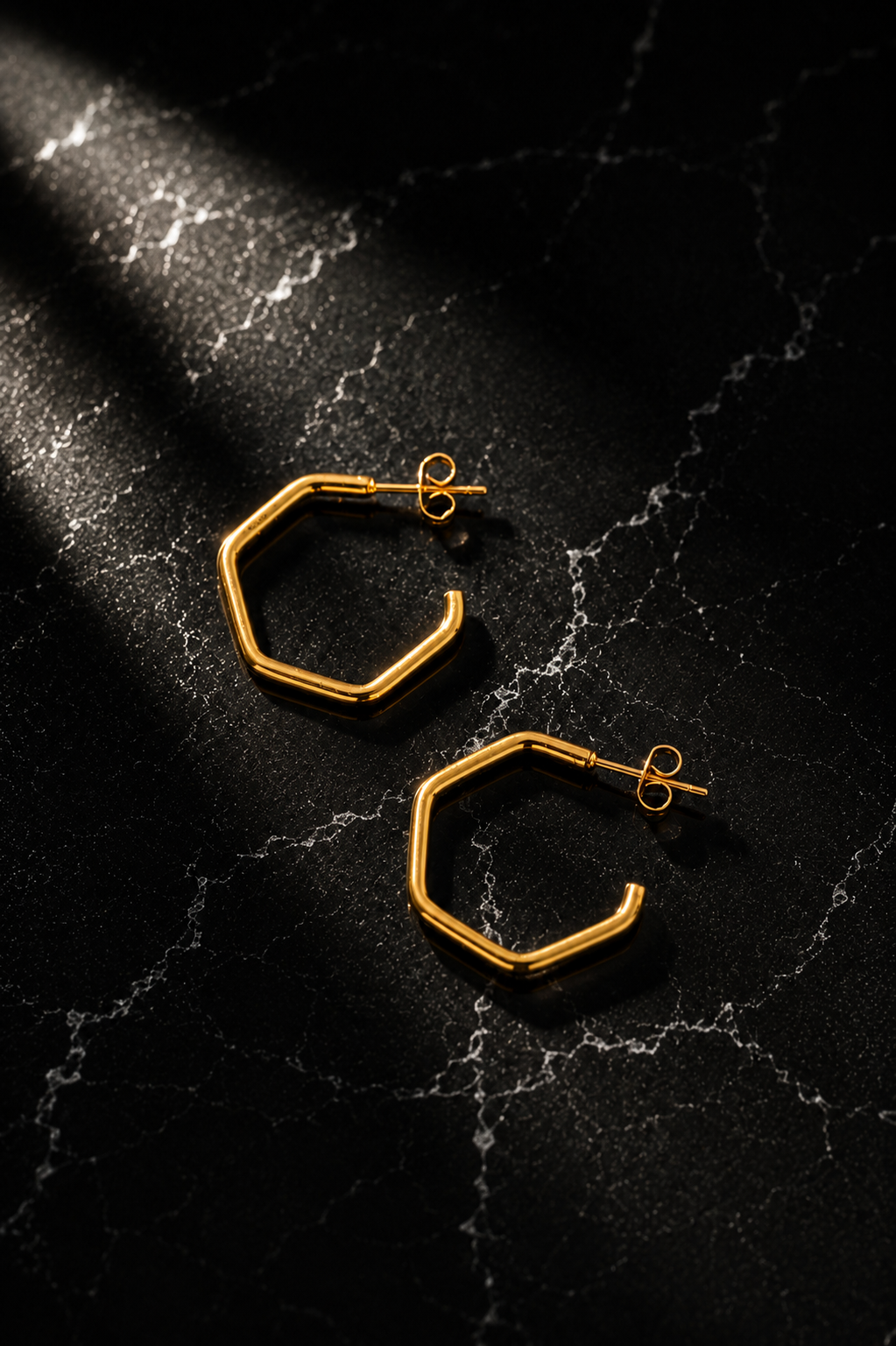 Samarrah Hoops featuring geometric stainless steel hoops with 18kt gold plating displayed on a black marble surface.