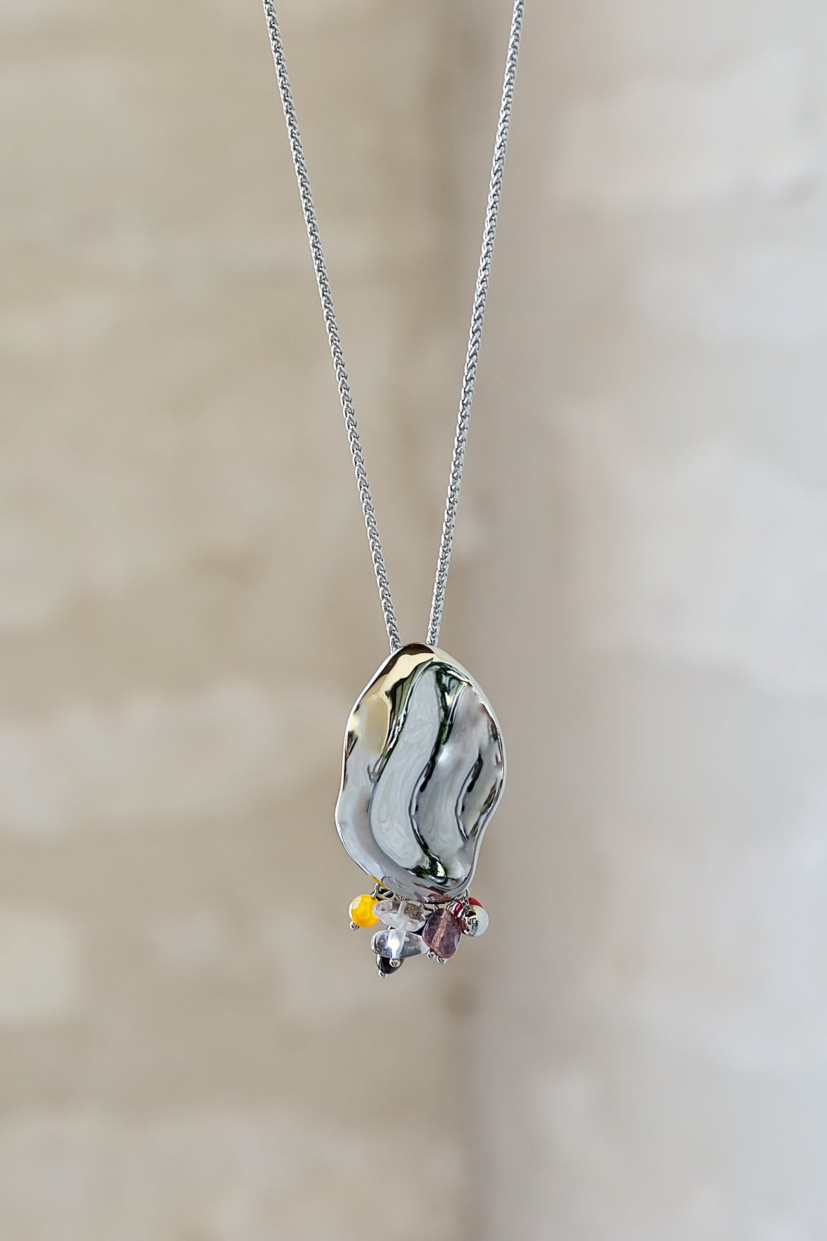 Close-up of the Sculptura Necklace by VEITA Jewelry showing the fluid silver-tone pendant and natural stone details.
