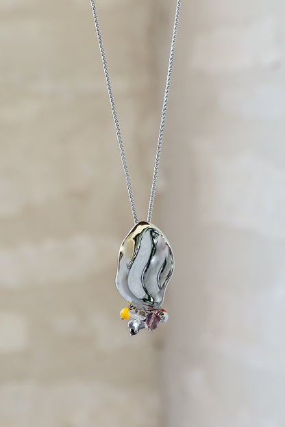 Close-up of the Sculptura Necklace by VEITA Jewelry showing the fluid silver-tone pendant and natural stone details.