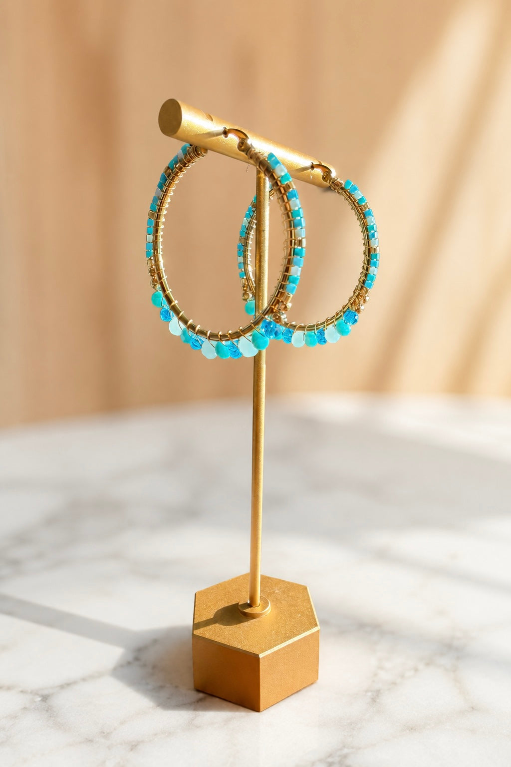 Seaside Earrings featuring hand-beaded light blue beads on 18kt gold plated stainless steel hoop earrings.