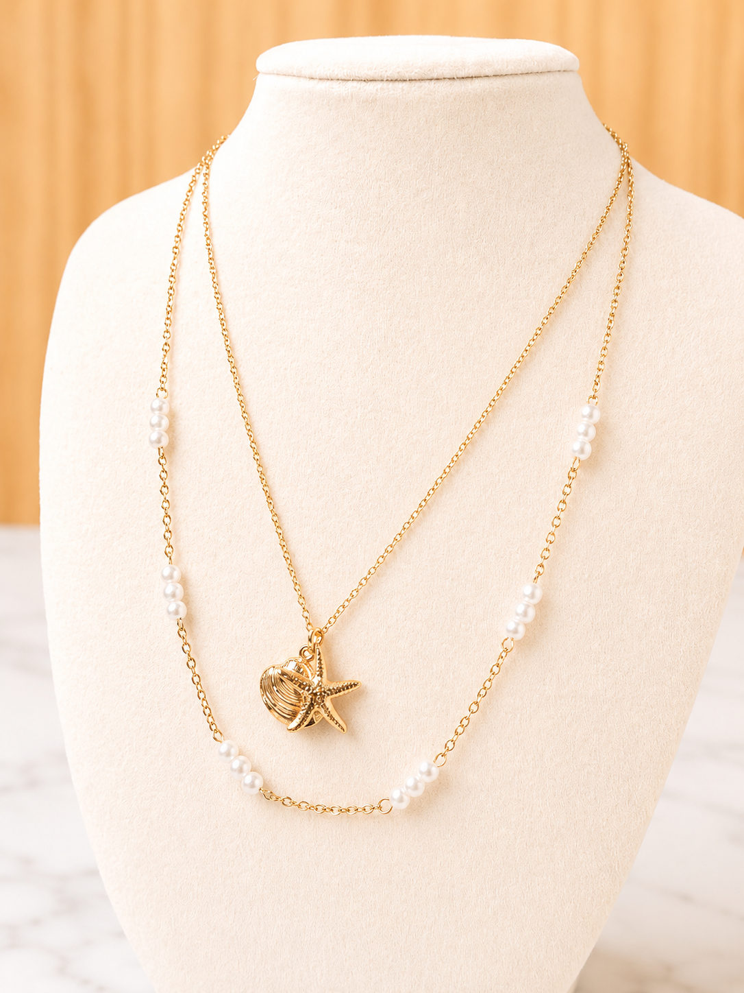 Shoreline Necklace in gold featuring shell and starfish charms on an 18kt gold plated stainless steel chain, inspired by sun-drenched coastal style.