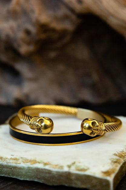 Gold bracelet with skull designs on a stone surface