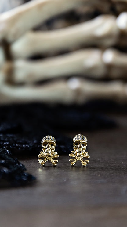Gold plated Skull Micro Stud Earrings by VEITA Jewelry featuring miniature skull designs with sparkling crystal accents, displayed against a dark background.